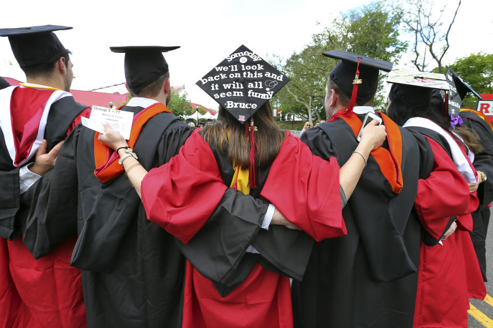 FILE - In this May 15, 2016 file photo, students embrace as they arrive for the Rutgers graduation ceremonies in Piscataway, N.J.  More Americans are getting buried by student debt, causing delays in home ownership, limiting how much people can save and leaving taxpayers at risk as many loans go unpaid. (AP Photo/Mel Evans)