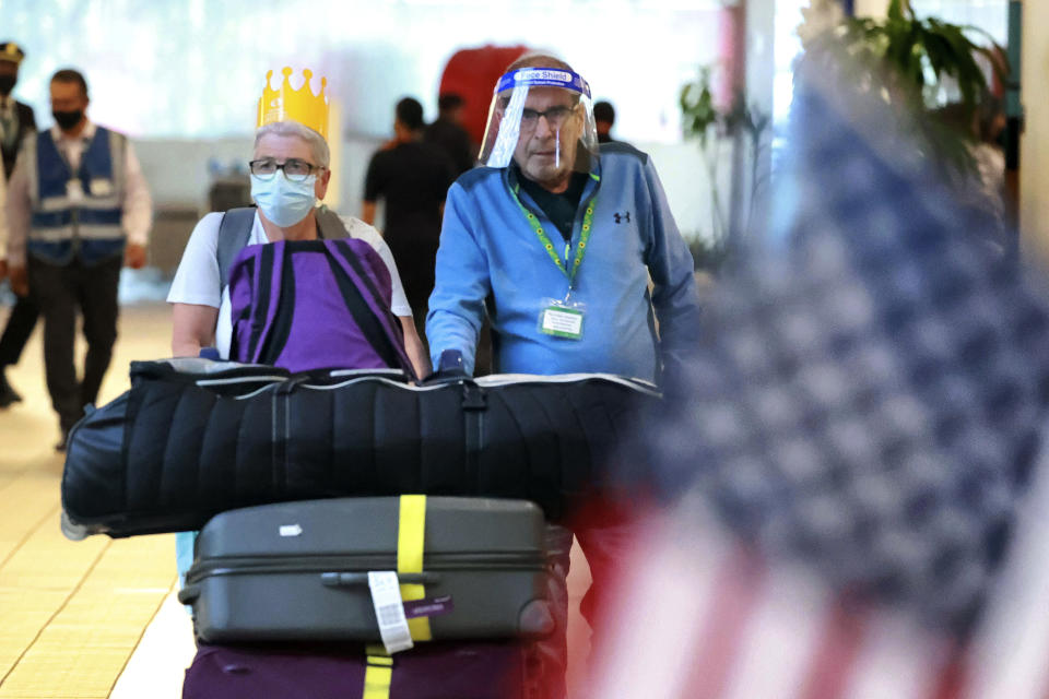 FILE - A couple arriving on a Virgin Atlantic flight from Manchester, England to Orlando International Airport head to baggage claim on Nov. 8, 2021, in Orlando, Fla. Beginning next week, travelers heading to the U.S. will be required to show evidence of a negative test for the virus within one day of boarding their flight. The previous period was three days. (Joe Burbank/Orlando Sentinel via AP, File)