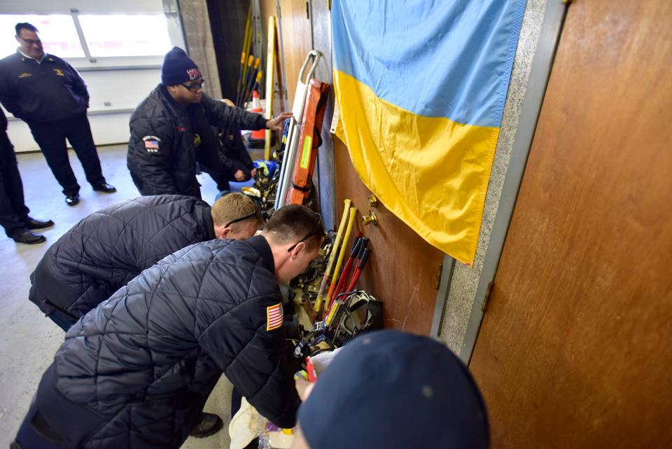 As Fire Chief Patrick Trentacost (upper L),looks on as firefighters sort out personal protective equipment including air tanks, masks, gloves and turnout coats that will be donated to Ukraine, at Eastside Fire House in Passaic on Thursday, March 3, 2022.