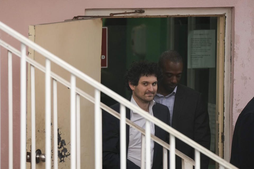 FTX founder Sam Bankman-Fried, left, is escorted from the Magistrate Court in Nassau, Bahamas, Wednesday, Dec. 21, 2022, after agreeing to be extradited to the U.S. (AP Photo/Rebecca Blackwell)