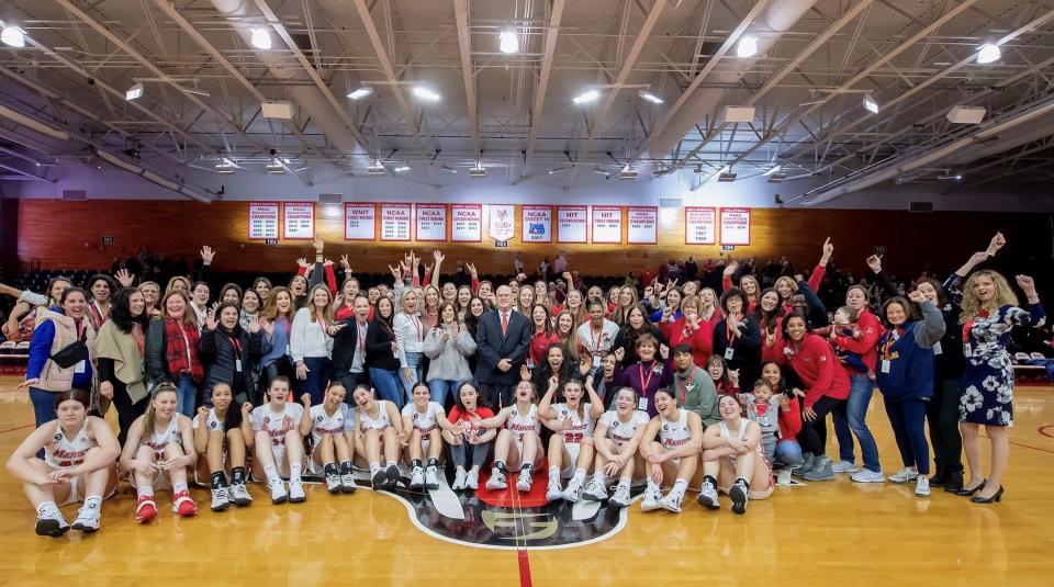 Marist College women's basketball coach Brian Giorgis, center, poses while surrounded by current and former players who returned to the school Saturday for his final home game before retirement.