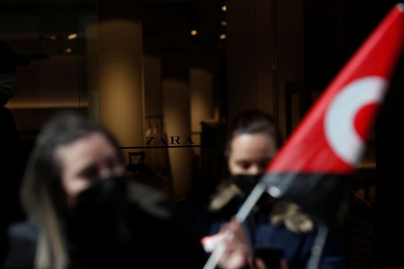 People hold flags from Spain's CGT labour union as they protest outside a Zara clothing store in Madrid