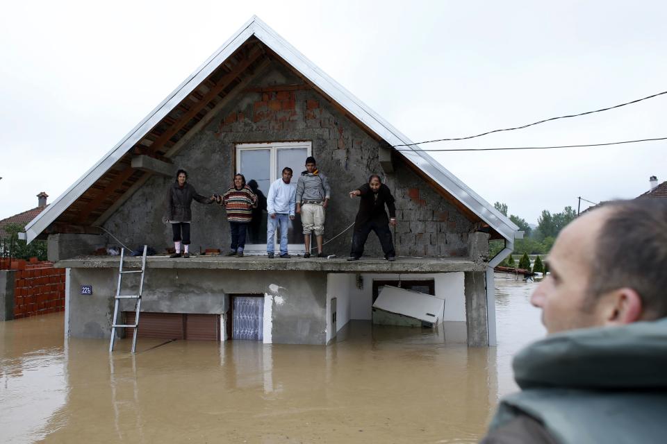 People stand on a terrace of their flooded house as they wait before being evacuated in the town of Obrenovac, east from Belgrade May 16, 2014. (REUTERS/Marko Djurica)