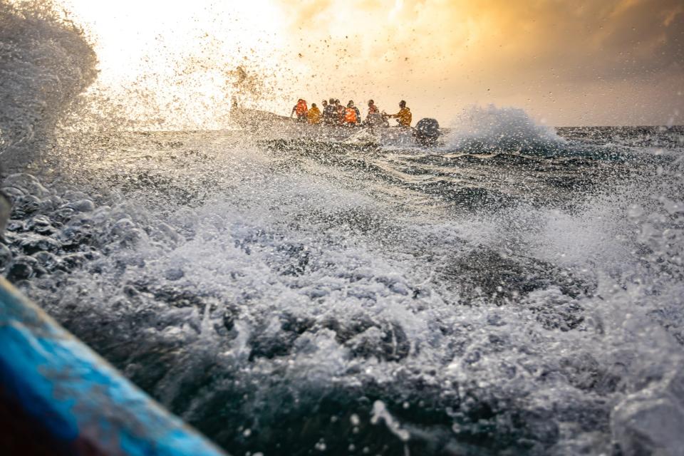 A team of scientific divers on board a small boat heads for a dive in rough seas.