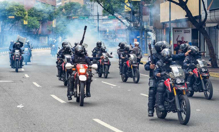 Membros do esquadrão de choque da Guarda Nacional afastam-se do gás lacrimogêneo no bairro de Chacao enquanto opositores do presidente venezuelano Nicolás Maduro participam de uma manifestação, em Caracas, em 30 de julho de 2024. 