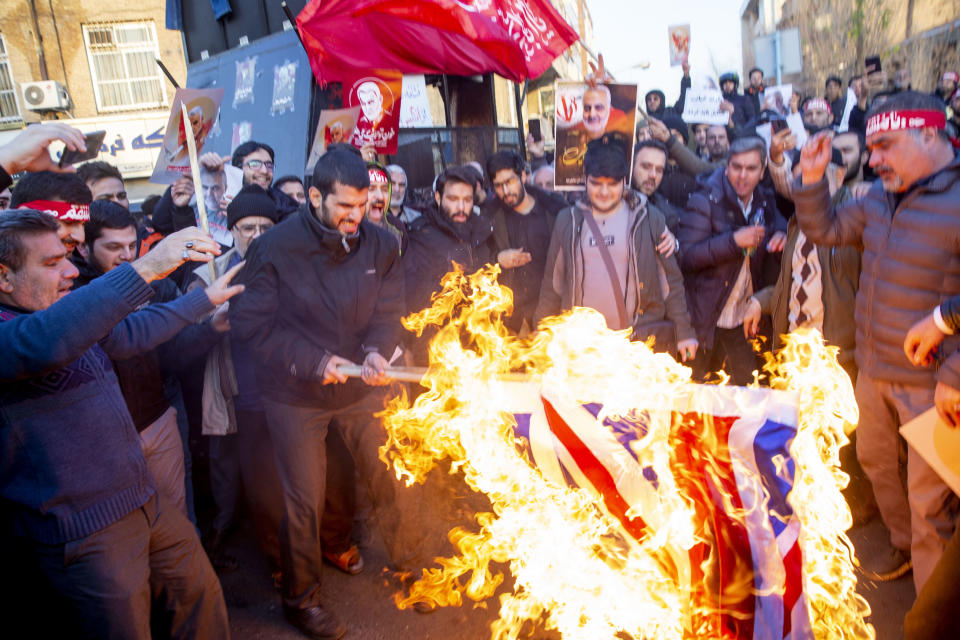 TEHRAN, IRAN - JANUARY 12: Protesters chant slogans and hold up posters of Gen. Qassem Soleimani while burning representations of British and Israeli flags, during a demonstration in front of the British Embassy on January 12, 2020 in Tehran, Iran. A candlelight vigil held late on Saturday in Tehran, to remember the victims of the Ukrainian plane crash, turned into a protest with hundreds of people chanting against the country's leaders including Supreme Leader Ayatollah Ali Khamenei and police dispersing them with tear gas. Police briefly detained the British ambassador to Iran, Rob Macaire, who said he went to the Saturday vigil without knowing it would turn into a protest. (Photo by Majid Saeedi/Getty Images)