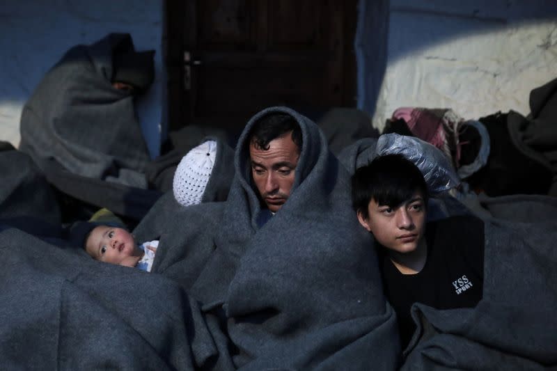 Migrants, who arrived the previous day on a dinghy after crossing part of the Aegean Sea from Turkey, are seen covered with blankets near the village of Skala Sikamias, on the island of Lesbos