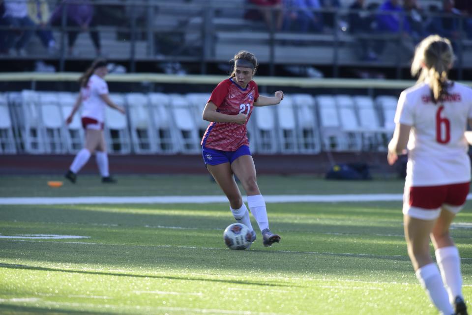 St. Clair's Ella Farkas passes the ball off to her teammate during the Saints' 2-0 win over St. Clair Shores Lake Shore in a district final at East China Stadium on Thursday, June 2, 2022.