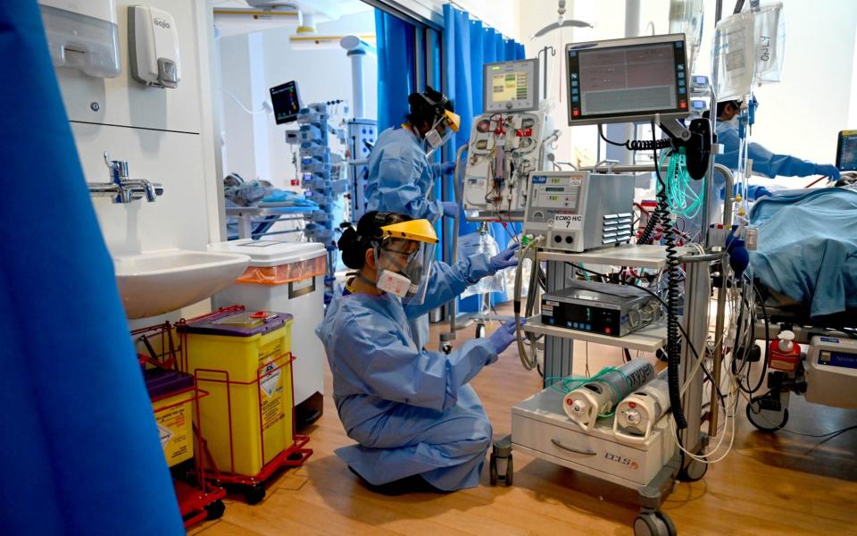 Clinical staff wear personal protective equipment (PPE) while caring for a patient in the Intensive Care unit (ICU) at the Royal Papworth Hospital, in Cambridge, in May 2020 - Neil Hall/EPA