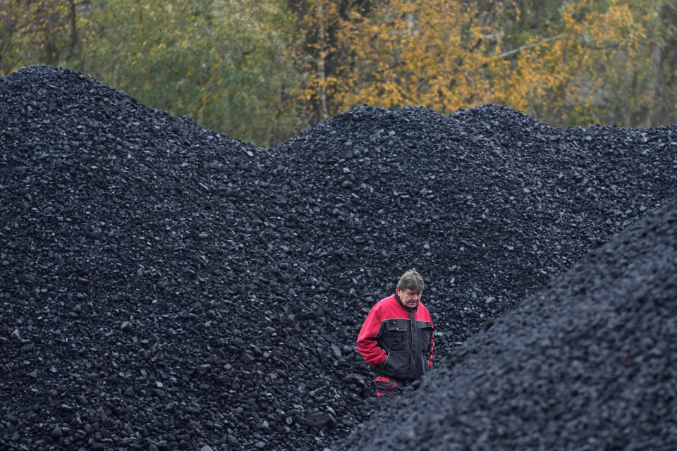 A worker walks past piles of coal at a selling point in Ostrava, Czech Republic, Friday, Nov. 11, 2022. High energy prices linked to Russia's war in Ukraine have paved the way for coal’s comeback, endangering climate goals and threatening health from increased pollution. (AP Photo/Petr David Josek)