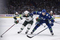 Minnesota Wild's Joel Eriksson Ek (14), of Sweden, skates with the puck past Vancouver Canucks' Tyler Myers during the third period of an NHL hockey game, Tuesday, Oct. 26, 2021 in Vancouver, British Columbia. (Darryl Dyck/The Canadian Press via AP)