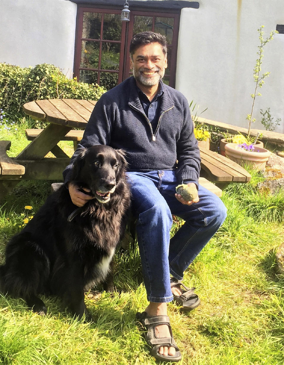 In this image taken on April 9, 2020 Dr. Poorna Gunasekera poses for a photo with his dog Barney at his home in the village of Filham, Devon, England, minutes after returning from hospital. At his darkest moment in his struggle with the coronavirus, Dr. Poorna Gunasekera glimpsed the first rays of light when three of his former students came to help. Having endured a severe deterioration in his COVID-19 symptoms after around 12 days of contracting the virus, Gunasekera was rushed to Derriford Hospital in Plymouth, in the early hours of March 30. "It was wonderful that during that time, two of my former students, who are doctors, and another who was a nurse, actually came and they identified themselves," he told The Associated Press over several interviews following his release from hospital on April 9. (George Petrie via AP)