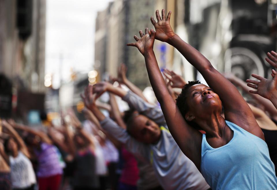 Yoga instructor Tracye Warfield, right, participates in a yoga class in Times Square during the 13th annual Solstice in Times Square, Sunday, June 21, 2015, in New York. Warfield was one of several thousand who practiced yoga during six different classes held throughout the day to mark the summer solstice. (AP Photo/Julie Jacobson)