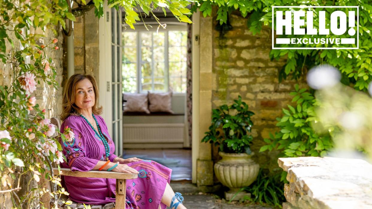 Penelope Chilvers in purple dress and blue shoes sitting outside at Cotswolds home