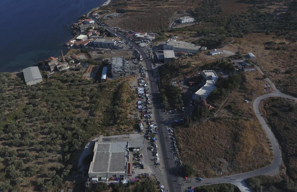 Migrants take part in a rally as riot police block the road near Mytilene town, on the northeastern island of Lesbos, Greece, Friday, Sept. 11, 2020. Thousands of refugees and migrants left without shelter on the Greek island of Lesbos after fires destroyed the overcrowded Moria camp held a brief protest Friday on a road to the island's main town, demanding to be allowed to leave. (AP Photo/Panagiotis Balaskas)