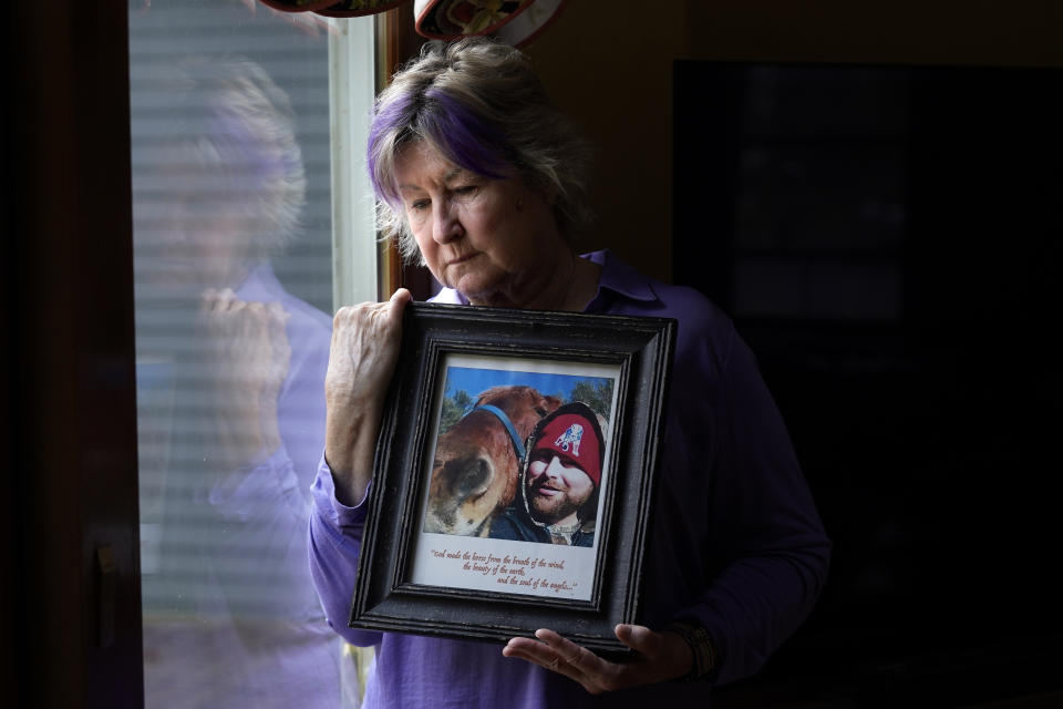 Lynn Wencus, of Wrentham, Mass., stands for a photograph while holding a photo of her son Jeff at her home, in Wrentham, Tuesday, Nov. 7, 2023. Wencus lost Jeff to a heroin overdose in 2017. Families who lost loved ones to overdose are divided over OxyContin maker Purdue Pharma's plan to settle lawsuits over the toll of opioids with governments. It could provide billions to address an overdose epidemic and pay some victims. But it would also protect members of the Sackler family who own the company from future lawsuits. (AP Photo/Steven Senne)