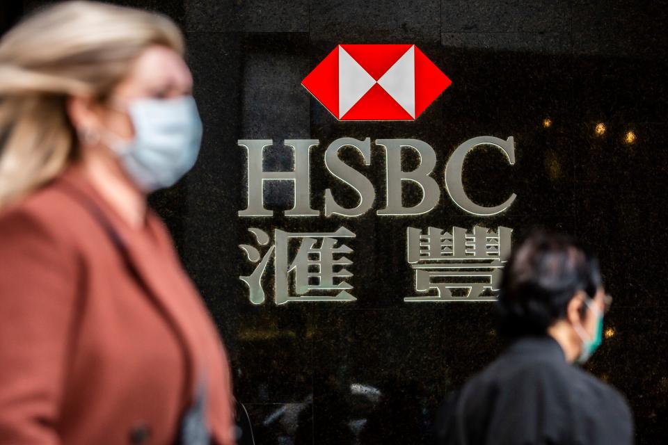 A woman (L) walks past a HSBC sign in Hong Kong on February 18, 2020. - The London-based, Asia-focused behemoth HSBC is expected to release its Q4 and 2019 results later on February 18. (Photo by ISAAC LAWRENCE / AFP) (Photo by ISAAC LAWRENCE/AFP via Getty Images)