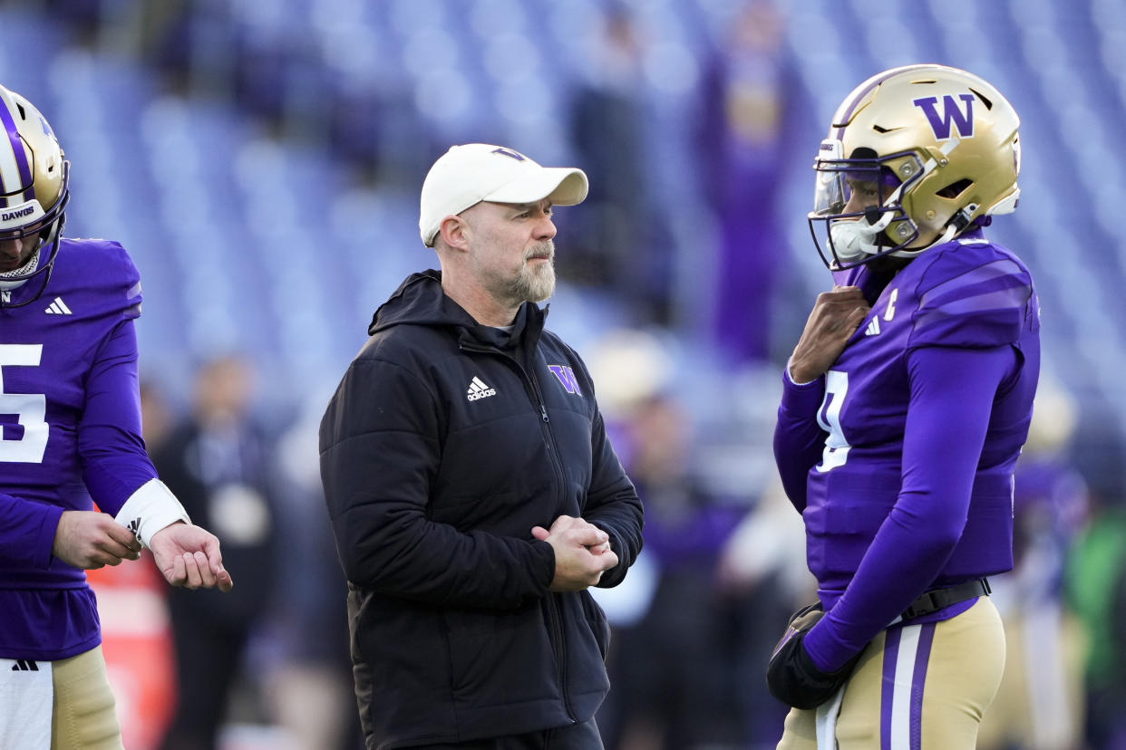 Washington offensive coordinator Ryan Grubb, center, talks with quarterback Michael Penix Jr. (9) during warm ups before an NCAA college football game against Washington State, Saturday, Nov. 25, 2023, in Seattle. (AP Photo/Lindsey Wasson)