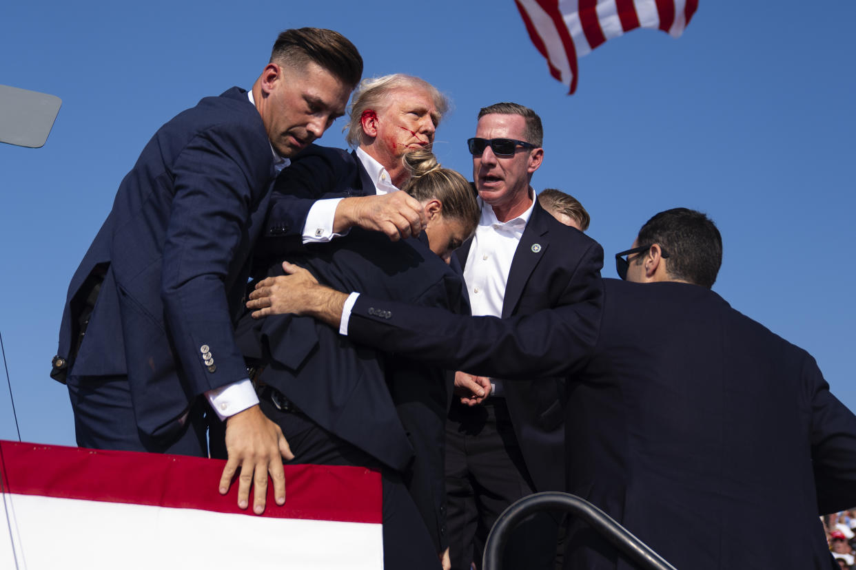 Trump, with blood on the right side of his face, is carried off stage by Secret Service agents.