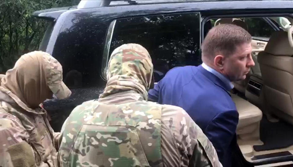 In this image distributed by Russian Investigative Committee, Sergei Furgal, the governor of the Khabarovsk region is escorted by Russian Federal Security Service (FSB, Soviet KGB successor) and Russian Investigative Committee agents in Khabarovsk, Russia, Thursday, July 9, 2020. Sergei Furgal, the governor of the Khabarovsk region along the border with China, was arrested in Khabarovsk and was flown to Moscow and has been arrested on charges of involvement in multiple murders. (The Investigative Committee of the Russian Federation via AP)