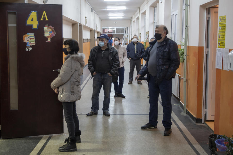 Voters respecting social distance wait to cast their ballot during parliamentary elections in the town of Bankya near capital Sofia, Bulgaria on Sunday, April 4, 2021. Bulgarians are heading to the polls on Sunday to cast ballots for a new parliament after months of anti-government protests and amid a surge of coronavirus infections. (AP Photo/Visar Kryeziu)