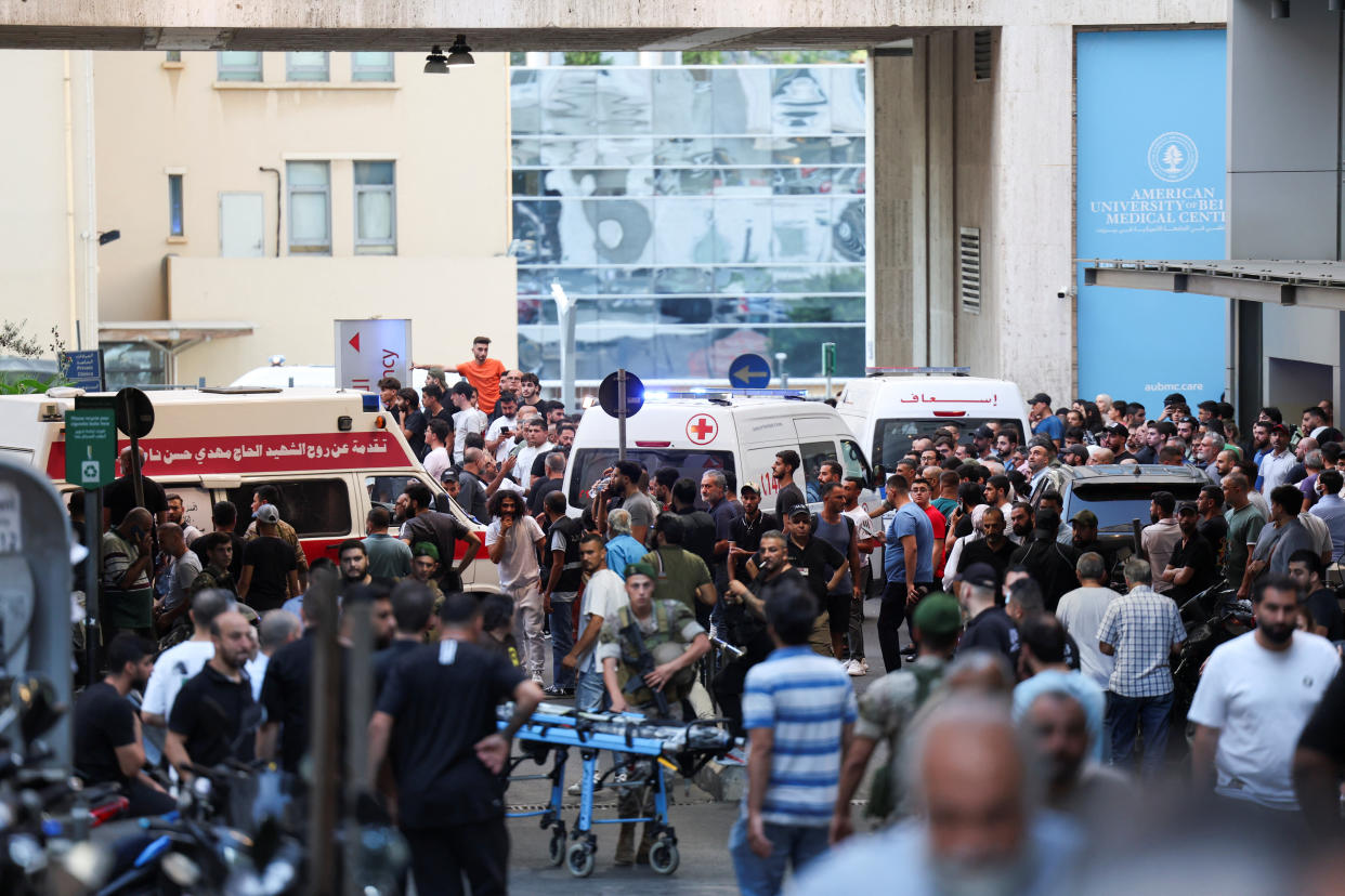 Ambulances, surrounded by dozens of people, arrive at a hospital in Beirut.