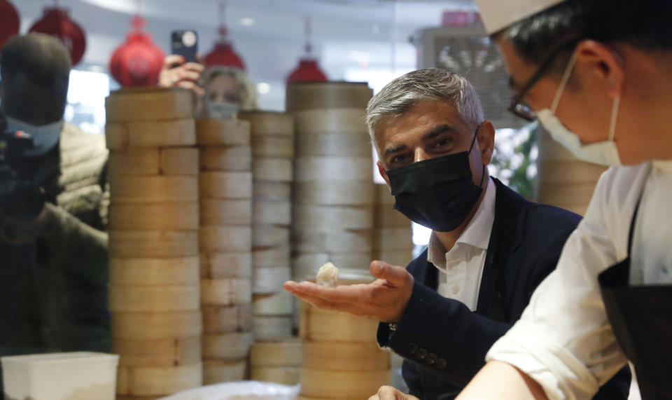 Mayor of London Sadiq Khan, second right attempts to prepare dumplings with head chef Ling Bing, during a visit to Dumplings Legend in China Town central London, Monday, May 17, 2021. Pubs and restaurants across much of the U.K. are opening for indoor service for the first time since early January even as the prime minister urged people to be cautious amid the spread of a more contagious COVID-19 variant. (AP Photo/Alastair Grant)