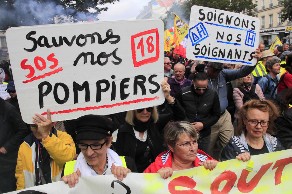 Firemen and hospital staff demonstrate with posters reading "Save our firefighters", left, and "treat our caregivers" as they protest on wages, working conditions and pensions, Tuesday, Oct. 15, 2019 in Paris. (AP Photo/Michel Euler)