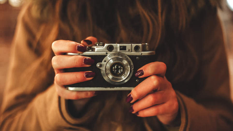  A girl holding a vintage film camera. 