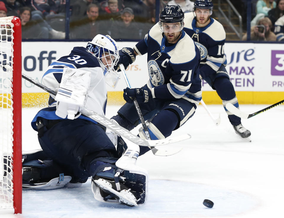 Winnipeg Jets' Laurent Brossoit, left, makes a save against Columbus Blue Jackets' Nick Foligno during the second period of an NHL hockey game Wednesday, Jan. 22, 2020, in Columbus, Ohio. (AP Photo/Jay LaPrete)