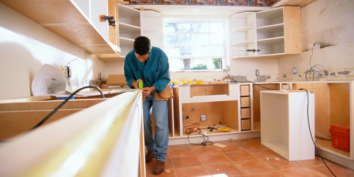 A man measures a counter for a kitchen renovation