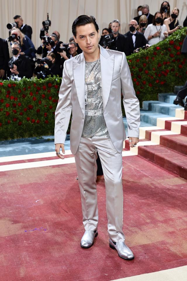 Cole in a silver metallic suit and shoes. He has a silver chainmail shirt on under with silver bondage-like straps.
