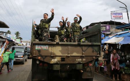 Government troops wave at residents and motorists as they travel back from their five-month combat duty in Marawi. REUTERS/Romeo Ranoco