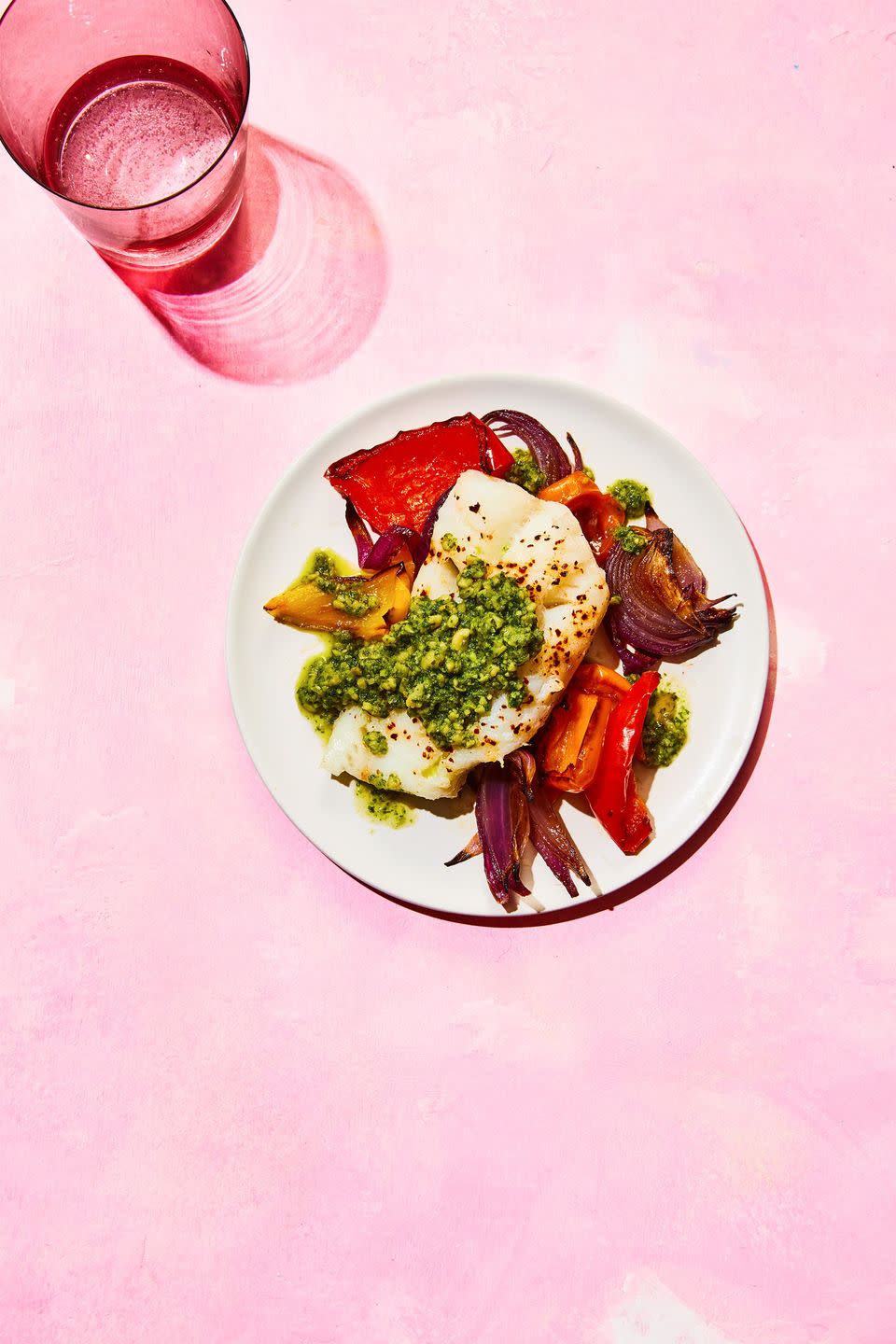 white fish over roasted veggies on a white plate