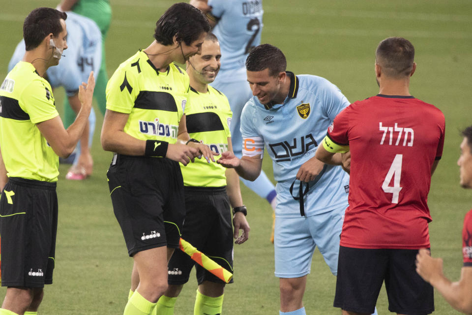 Player Idan Vered, right, checks the fingernails of referee Sapir Berman, center left, during an Israeli Premier League soccer match between Hapoel Haifa and Beitar Jerusalem in the northern Israeli city of Haifa, Monday, May 3,2021. Israeli soccer's first transgender soccer referee took the field Monday for the first time since coming out publicly as a woman last week. (AP Photo/Sebastian Scheiner)