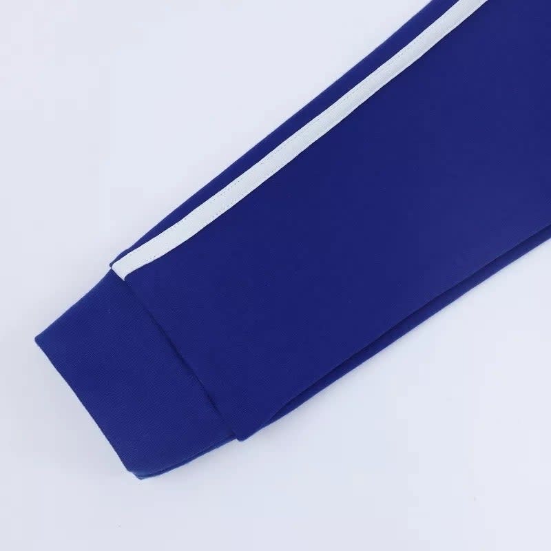 The arm of the jacket, which is royal blue and cuffed, with a white stripe down the length of the arm