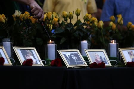 Candles are lit behind images of the victims killed in a shooting at Santa Fe High School during a vigil in League City, Texas, U.S., May 20, 2018. REUTERS/Jonathan Bachman