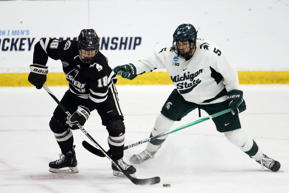 FILE - Western Michigan forward Wyatt Schingoethe (18) is pressured by Michigan State defenseman Artyom Levshunov (5) during the second period of an NCAA college hockey game in Maryland Heights, Mo., March 29, 2024. Levshunov is expected to be selected No. 2 by the Chicago Blackhawks in the upcoming NHL draft. (AP Photo/Colin E. Braley, File)