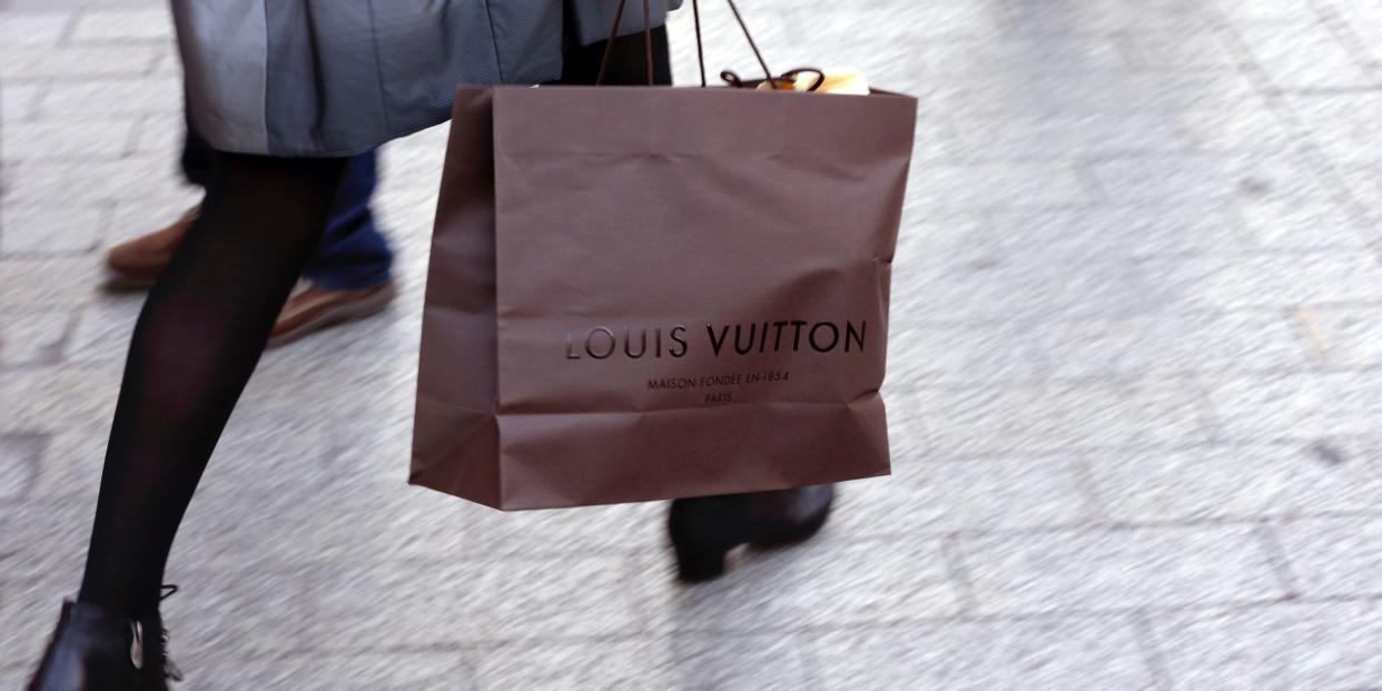 A woman walks with a Louis Vuitton shopping bag as she leaves a Louis Vuitton store in Paris September 24, 2013.