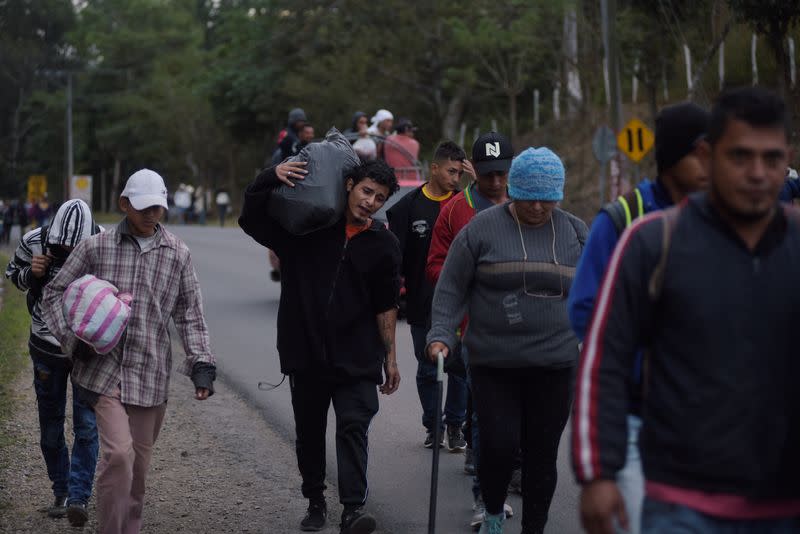 People, part of a caravan of migrants heading toward the United States, walk along a road in Agua Caliente