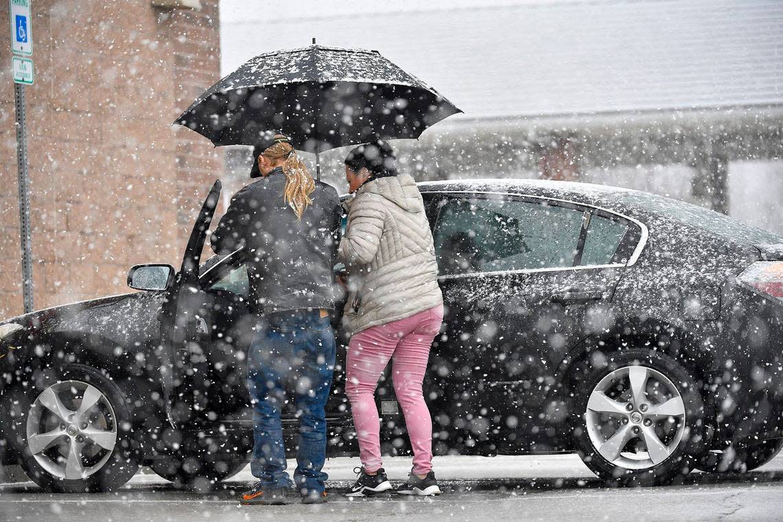 Nancy Varguez of Shawnee held an umbrella as Scott Rinker, an employee of Advance Auto Parts, helped her with a check engine light as snow fell on Monday, Jan. 8, 2024, in Shawnee, Kansas.