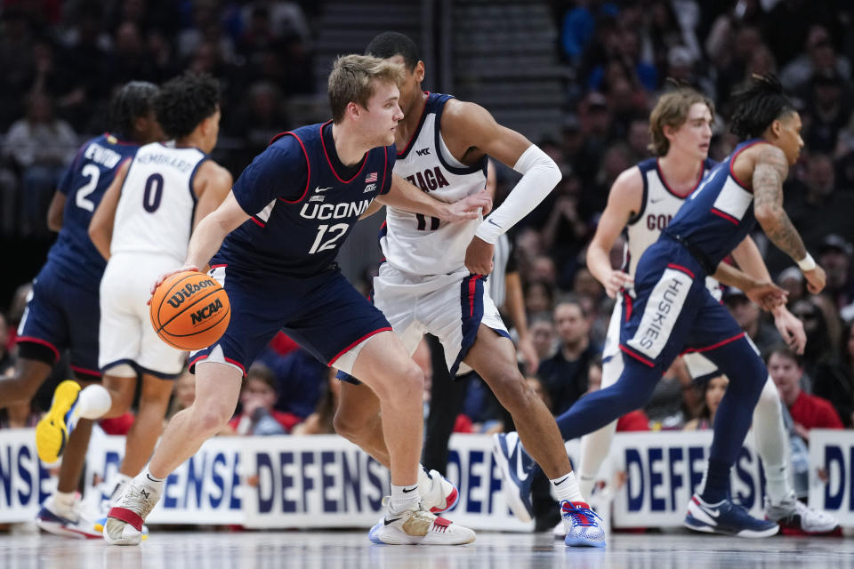 UConn guard Cam Spencer (12) is defended by Gonzaga guard Nolan Hickman (11) during the first half of an NCAA college basketball game Friday, Dec. 15, 2023, in Seattle. (AP Photo/Lindsey Wasson)