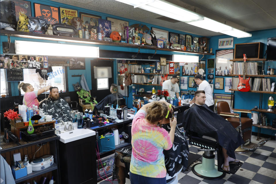 Musical memorabilia line the walls and shelves of the Glory Days Corner Barber Shop as Katie Hennenfent, left, cuts Ryan Hardwell's hair and as Sam Carr, right, attends to Jack Dechow in Galesburg, Ill., Wednesday, June 16, 2021. (AP Photo/Shafkat Anowar)