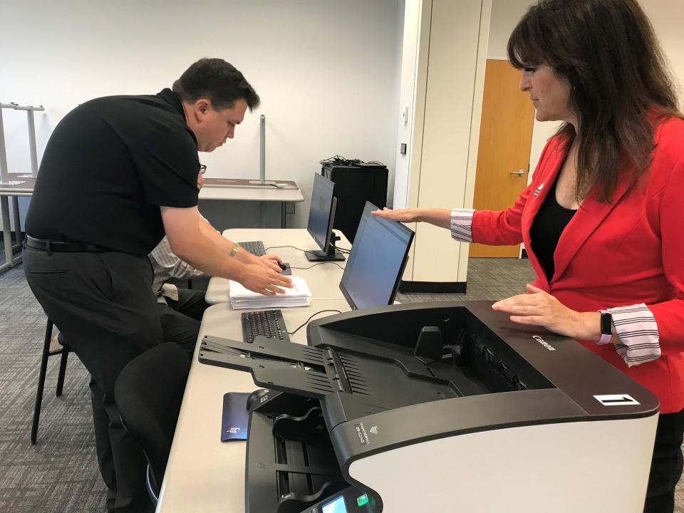 From left, assistant elections specialist Michael Kernen places test ballots beside a computer while Oakland County Clerk Lisa Brown, resting her left hand on the high-speed tabulator that seconds earlier had tallied the ballots, looks on during a test of the equipment for counting absentee ballots at the Oakland County Elections Division office in Pontiac on Wednesday, July 26, 2023.