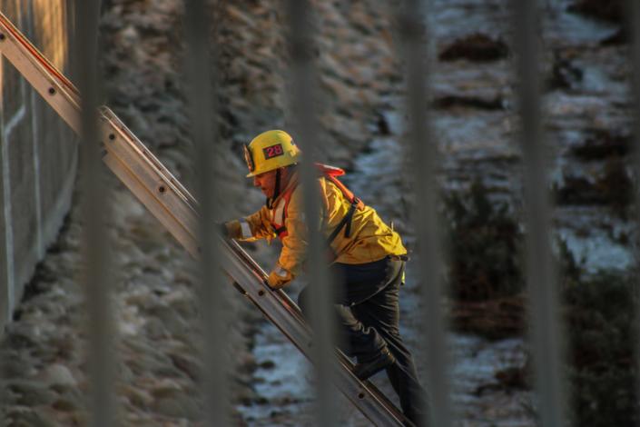 A Ventura County firefighter on a ladder above Santa Paula Creek, where a man was found dead on Dec. 31.