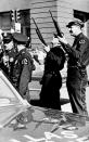 Police officers with guns ready look up the building where the shot came from that killed U.S. President John F. Kennedy while he was riding in an open limousine through downtown Dallas, Texas, on Nov. 22, 1963. (Photo: AP)