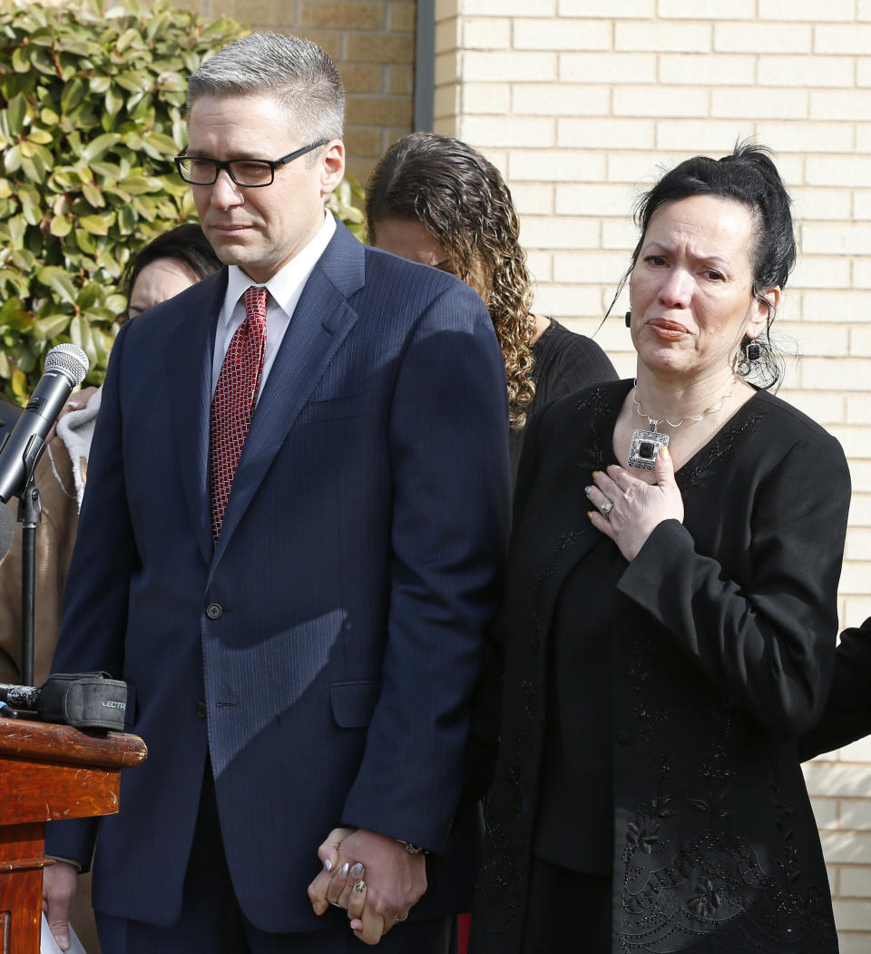Attorney Michael Brooks-Jimenez, left, holds the hand of Nair Rodriguez, right, as she speaks to the media at a news conference in Oklahoma City, Tuesday, Feb. 25, 2014. At the news conference, the family of Luis Rodriguez, a man who died after a struggle with police outside an Oklahoma movie theater, released a cellphone video of the incident that shows the man on his stomach on the ground with five officers restraining him, including one officer holding his head down. (AP Photo/Sue Ogrocki)
