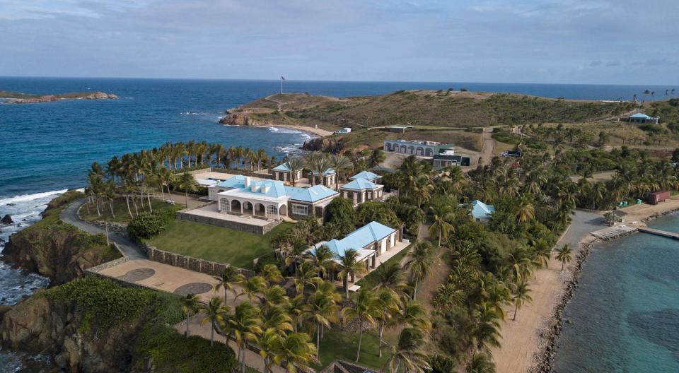 A palatial home is seen on an island surrounded by blue water.