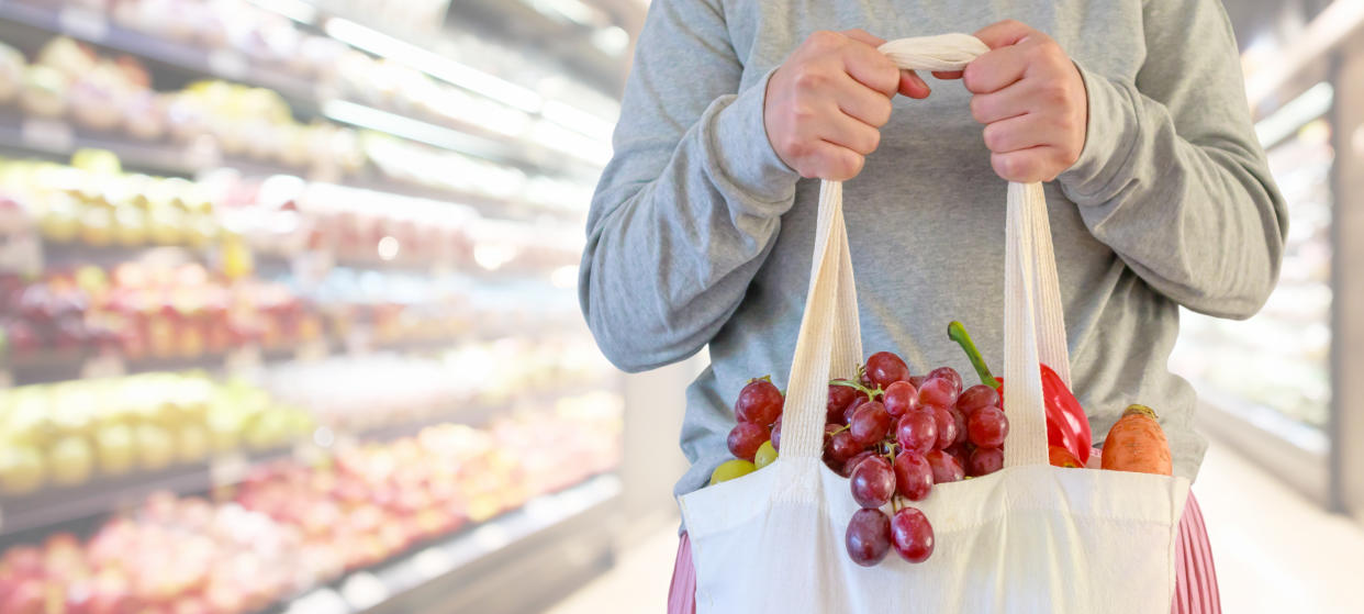 A woman holding a reusable grocery shopping bag in a supermarket. (PHOTO: Getty)