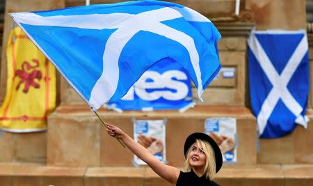 A woman waves a Scottish Saltire at a 'Yes' campaign rally in Glasgow, Scotland September 17, 2014. REUTERS/Dylan Martinez